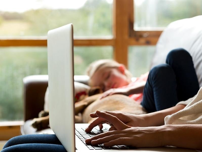 image of a person on a laptop with someone sleeping in the background
